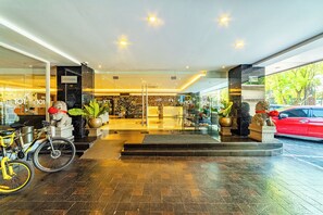 Een hotel lobby met een receptiebalie, een trap en een fiets buiten.