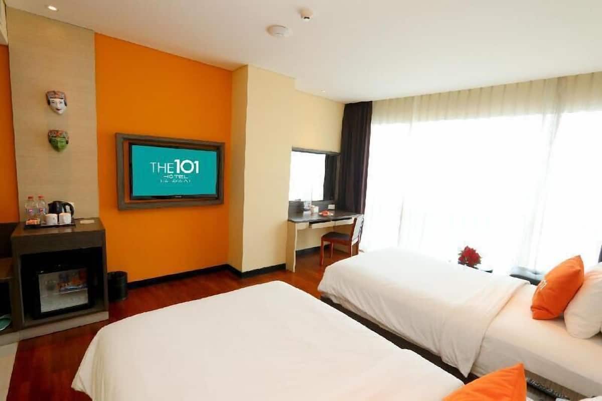Quarto de hotel com duas camas, uma escrivaninha, televisão e lareira.