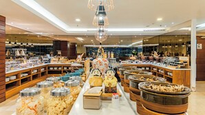 Un bufé con diversos alimentos, una figura decorativa en el centro y un letrero que indica la sección de condimentos.