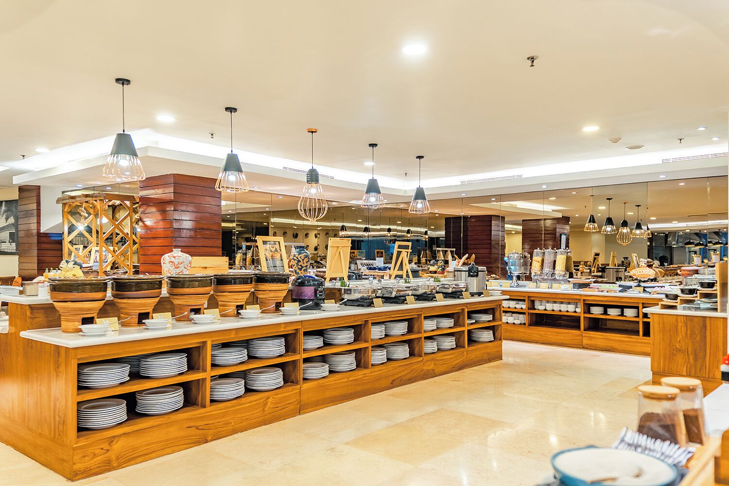 A buffet setup with multiple serving stations, wooden buffet counters, and hanging pendant lights.
