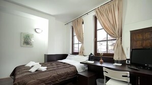 Una habitación de hotel con cama, escritorio, silla y televisor.