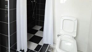 Un baño con ducha, inodoro y piso de estampado de cuadros.