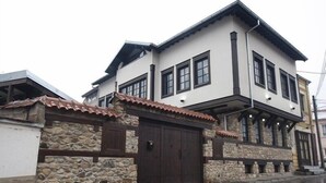 A two-story building with a stone facade, a dark brown wooden door, and a tiled roof. - Hotel Teatar (Bitola)