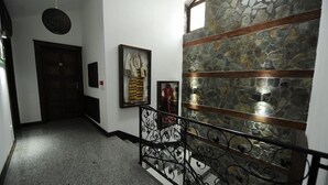A hallway with a stone wall, a metal railing, and framed artwork on the wall. - Hotel Teatar (Bitola)