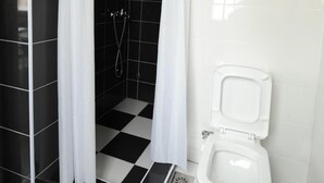 Un baño con ducha, inodoro y suelo a cuadros.