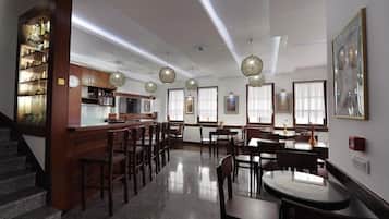 A spacious dining area with wooden tables and chairs, a kitchen area with cabinets and a refrigerator, and a staircase leading to an upper level.