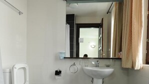 Un baño con inodoro, bidé, lavamanos y un pequeño taburete con toallas.