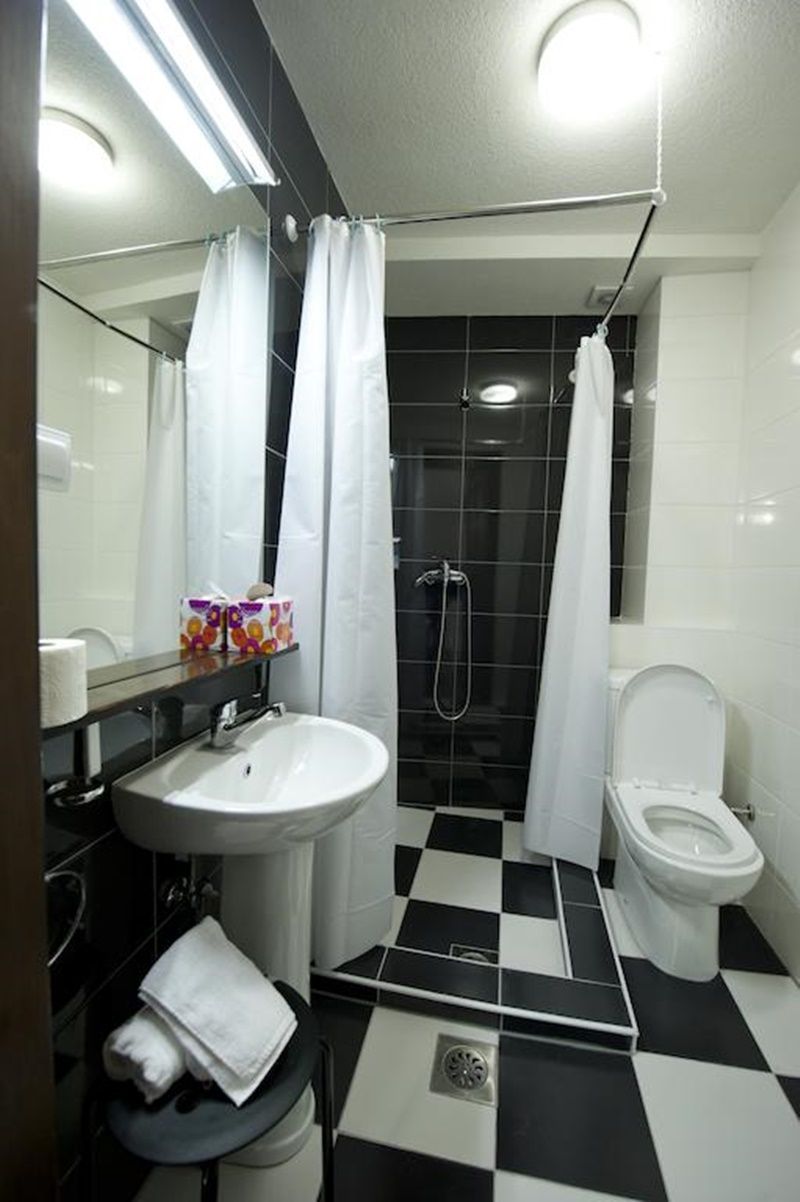 A bathroom with a black and white checkered floor, a white sink, a toilet, and a shower with white curtains.