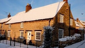 A stone house with a snow-covered roof and a small garden. - Luxuriously Restored Family Friendly 300 year old English Country Cottage  (Westow)