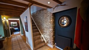A staircase with a stone wall, a wooden floor, and a blue wall with a mirror. - Luxuriously Restored Family Friendly 300 year old English Country Cottage  (Westow)