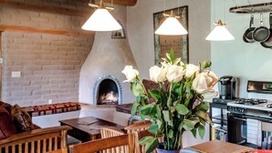A cozy living room with a fireplace, wooden furniture, and hanging pendant lights. - Stunning Mountain Views, Hot Tub, Sweeping Portal (Santa Fe)