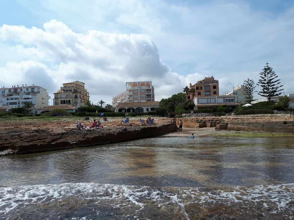 Vista sul fiume con edifici, una spiaggia sabbiosa e persone che si rilassano.