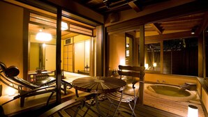A wooden deck with a hot tub, a lounge chair, and a table. - SEKIYA RESORT Bettei Haruki (Beppu)