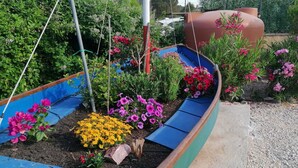 A garden with a blue and green planter bed containing various flowers and plants. - Country house with swimming pool and barbecue in Alghero (alghero)