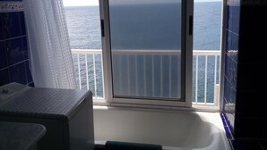 Un baño con vista al océano a través de una puerta corrediza.