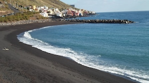 Enjoy the serene beach scene with gentle waves and a picturesque rocky breakwater.