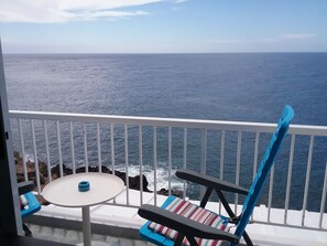 Ein Balkon mit Meerblick, einem Tisch und zwei Stühlen.