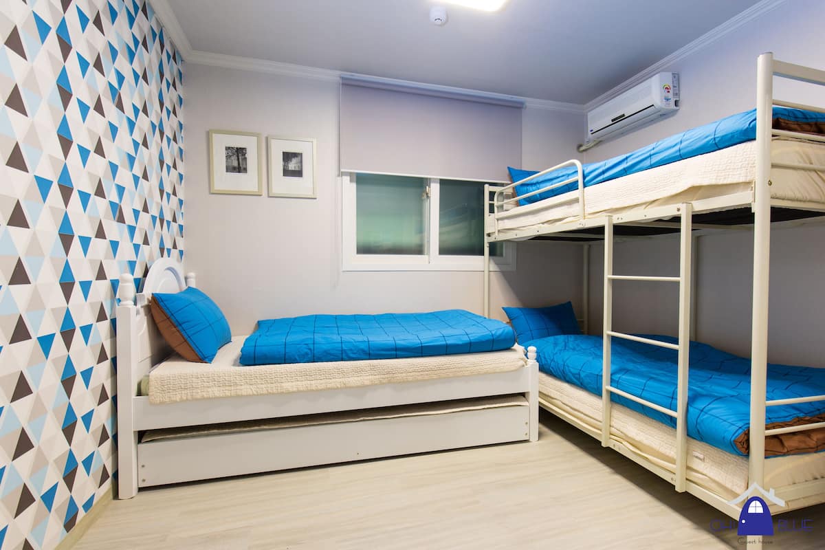 Une chambre avec des lits superposés, une fenêtre et un appareil de climatisation.