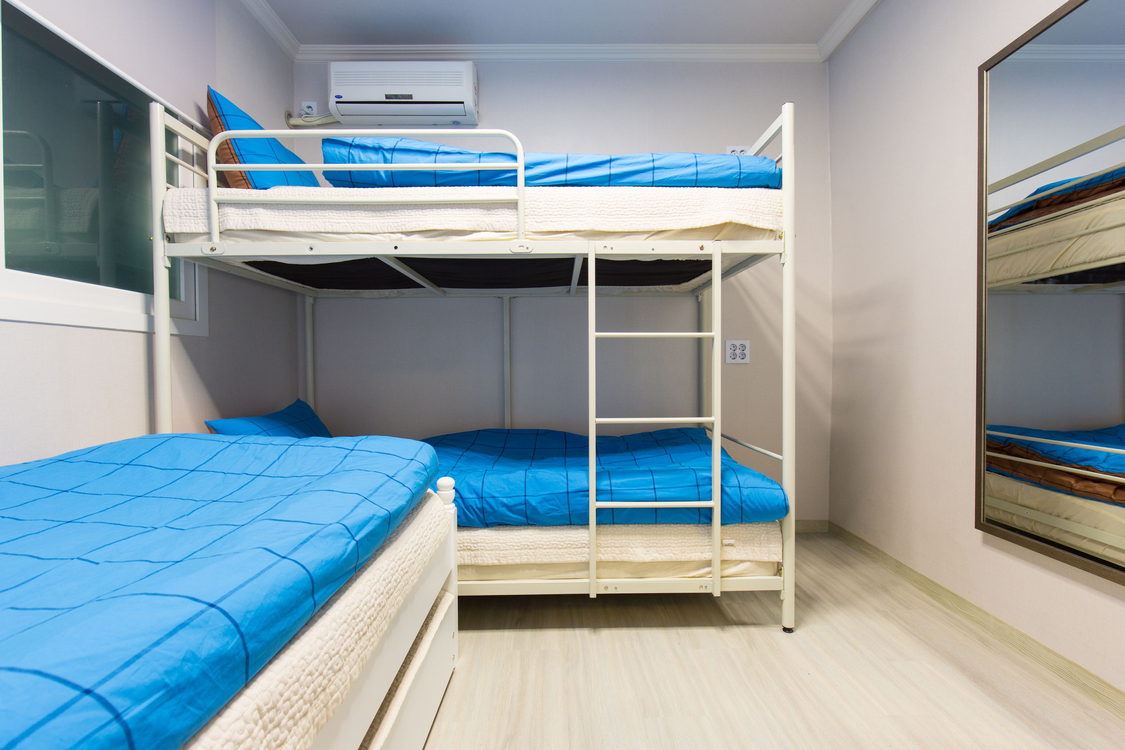 A bunk bed room with a window, a ladder, and an air conditioning unit.
