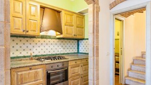 A kitchen with wooden cabinets, a gas stove, and a tiled backsplash.