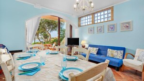 A dining area with a table set for four, a blue sofa, and a TV on a stand.