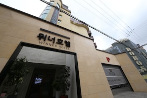 The exterior of the Winner Hotel with a modern facade, a visible entrance, and potted plants. - Winner Hotel (Jeonju)