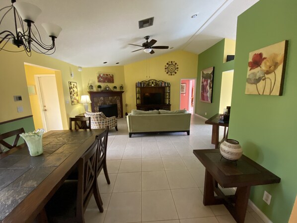 A living room with a fireplace, a sofa, a dining table, and chairs. - Comfortable 3-bedroom waterfront villa with heated pool (Deerfield)