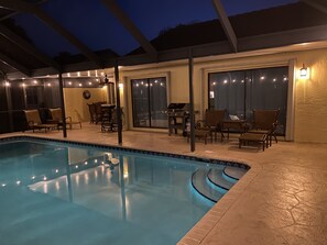 A swimming pool with a covered patio area, outdoor furniture, and a grill. - Comfortable 3-bedroom waterfront villa with heated pool (Deerfield)