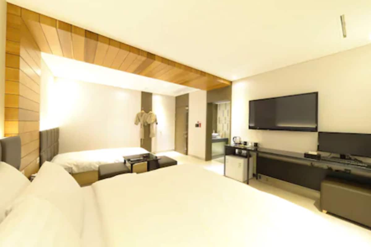 A modern hotel room with a large bed, a desk, a flat-screen TV, and a wardrobe.