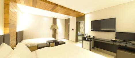 A modern hotel room with a large bed, a desk, a flat-screen TV, and a wardrobe.