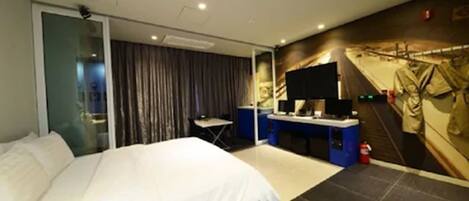 Habitación de hotel con cama, escritorio, televisión y perchero en la pared.
