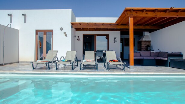 A poolside area with lounge chairs, a barbecue area, and a covered patio. - Villa with private heated pool and jacuzzi (PLAYA BLANCA)