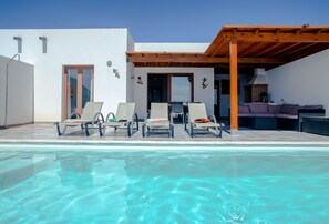 A poolside area with lounge chairs, a barbecue area, and a covered patio.