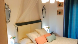 A bedroom with a bed, bedside tables, a nightstand, a red rug, a canopy bed, a chandelier, and wall decorations. - Design apartment, with a private terrace of 140 meters 20 meters from the sea and parking (Aguilas)