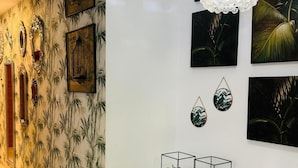 A hallway with a patterned wallpaper, a white console table with glass enclosures, and wall-mounted artwork including framed pictures and a hanging light fixture. - Design apartment, with a private terrace of 140 meters 20 meters from the sea and parking (Aguilas)