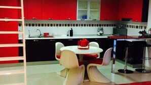 A modern kitchen with red cabinets, a white dining table with chairs, and a loft bedroom with a ladder. - Design apartment, with a private terrace of 140 meters 20 meters from the sea and parking (Aguilas)