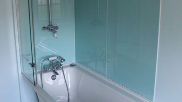 A bathroom with a glass-enclosed shower, a freestanding bathtub, and a white sink.