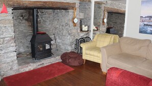 Una habitación con paredes de piedra, una chimenea, un sofá amarillo escocés y una alfombra roja.