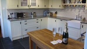 Una cocina con armarios blancos, una mesa de madera, una botella de champán y dos copas.
