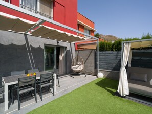 A patio with a table and chairs, a hanging chair, and a covered seating area.