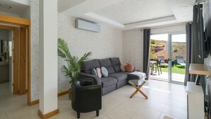 A modern living room with a grey sofa, a black armchair, and a glass coffee table. - Bali Sky Villa with Private Pool (San Bartolomé de Tirajana)