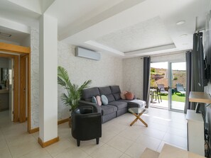 A modern living room with a grey sofa, a black armchair, and a glass coffee table. - Bali Sky Villa with Private Pool (San Bartolomé de Tirajana)