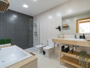 A modern bathroom with a bathtub, a shower, a toilet, and a bidet.