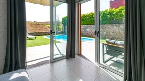 A modern room with a glass door leading to an outdoor swimming pool area. - Bali Sky Villa with Private Pool (San Bartolomé de Tirajana)