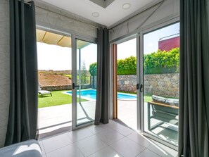 A modern room with a glass door leading to an outdoor swimming pool area. - Bali Sky Villa with Private Pool (San Bartolomé de Tirajana)