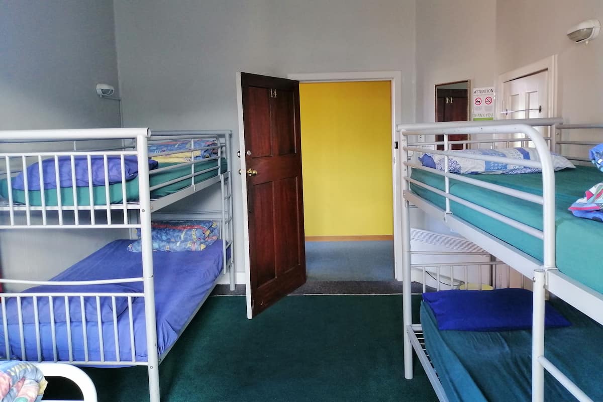 Un dormitorio con literas, una puerta y una pared amarilla.