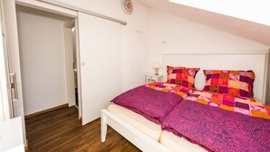 A bedroom with a bed, a nightstand, a lamp, and a closet.