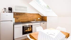 A compact kitchen with a built-in oven, a microwave, and a coffee maker. There is a dining table with chairs and a window above the sink.