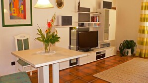 Un espace de vie compact comprenant une table à manger, un téléviseur et une bibliothèque.