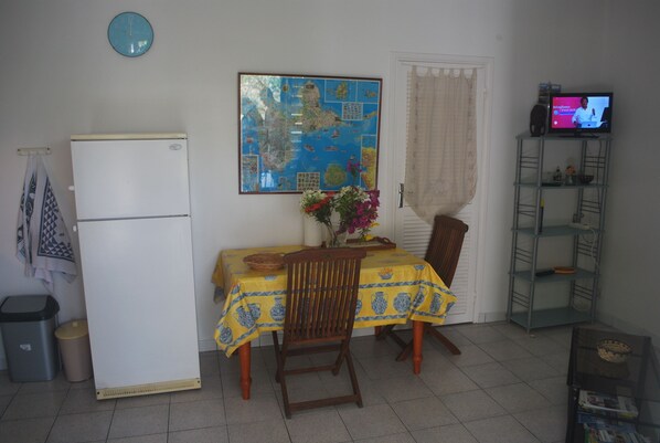 Un espacio habitable compacto con una mesa de comedor, sillas, un televisor y un mapa en la pared.